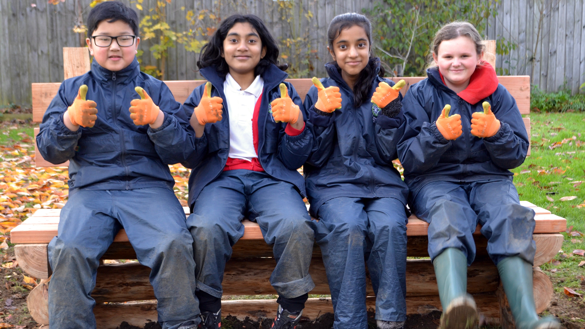 Children sitting on a bench they built in their school grounds under the My School, My Planet project.