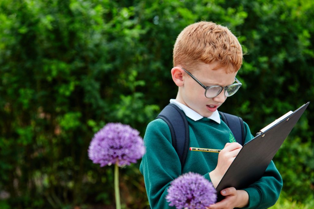 A school child working on a clipboard in the National Education Nature Park during an outdoor lesson about biodiversity.