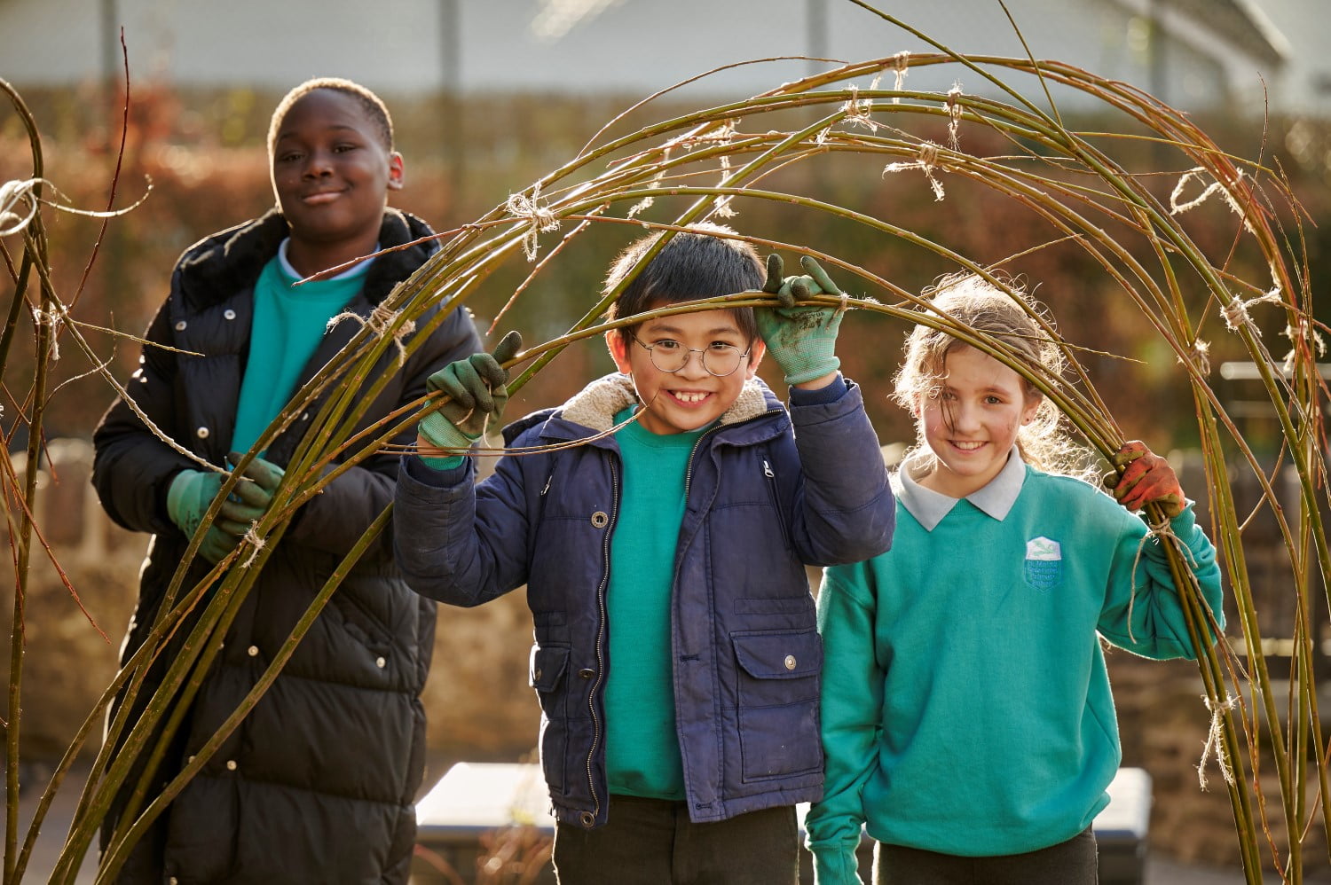 Children building a willow structure for plants to climb in their climate ready school grounds.