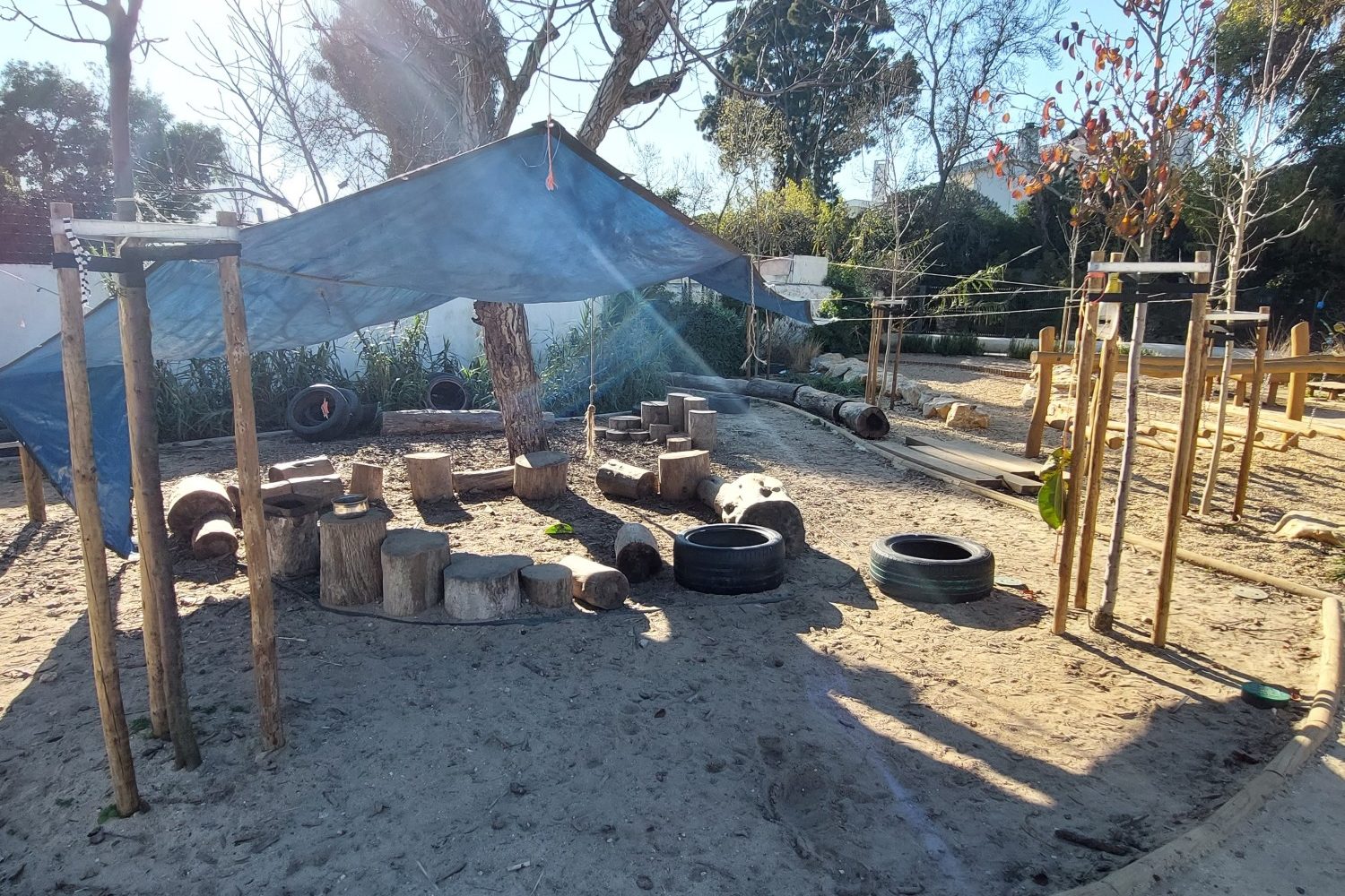 Log seating with a canopy to provide shelter from the sun in a sandy area of some climate ready school grounds.