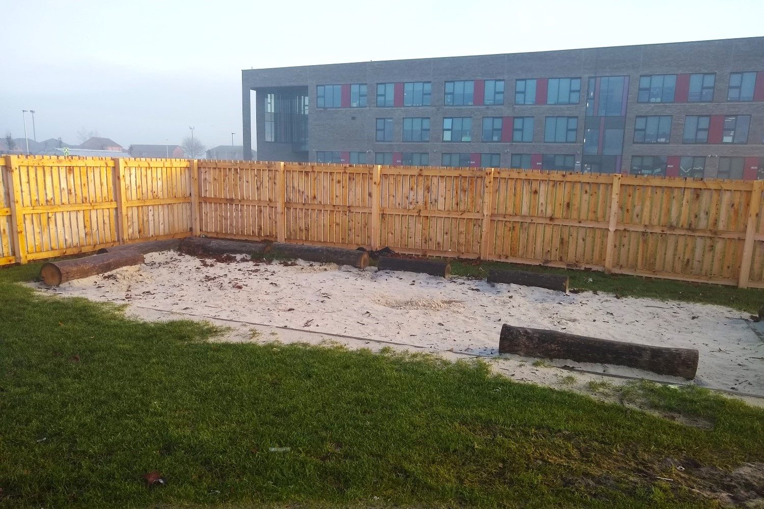 A fenced sandy area of some climate ready school grounds.