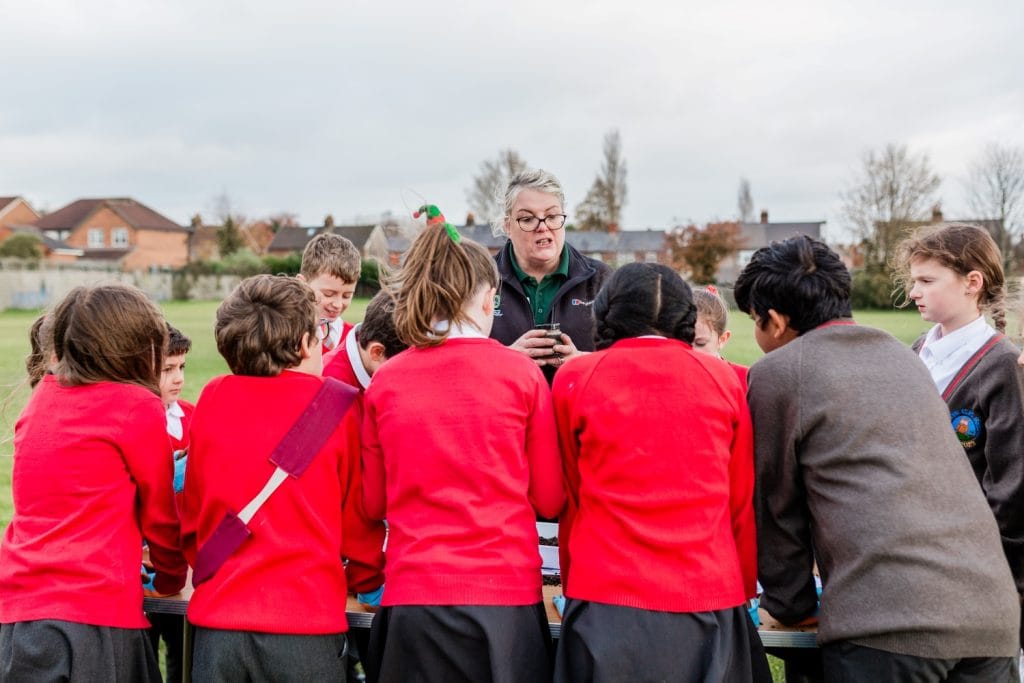 A trainer delivering an outdoor learning session to primary school children.