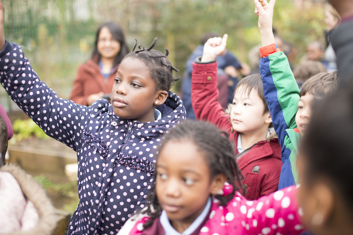 School children outdoors with their hands up