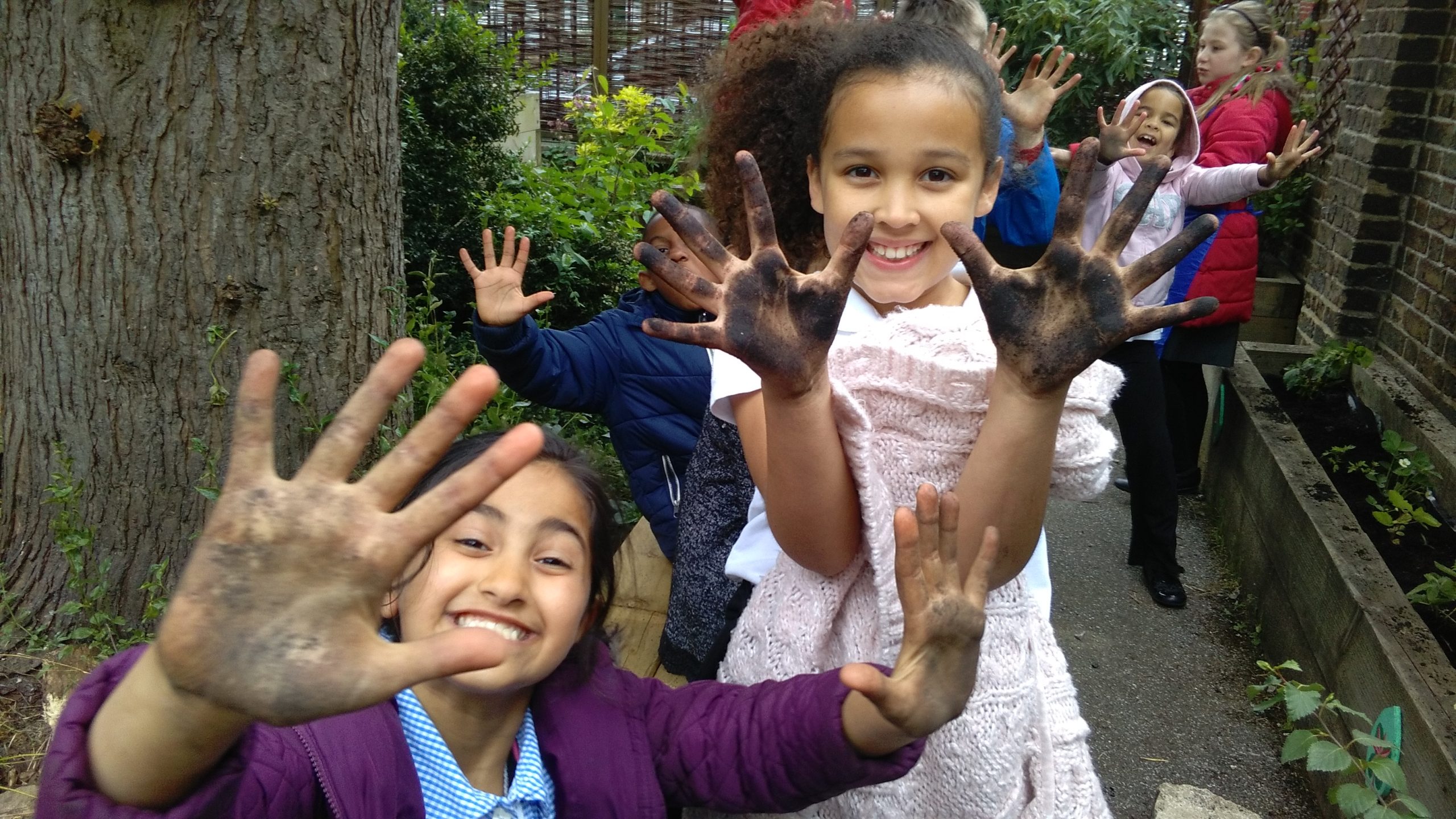 Two girls at school show their muddy hands