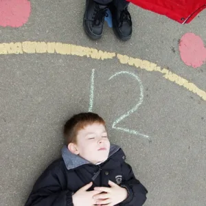Child lying on playground surface.