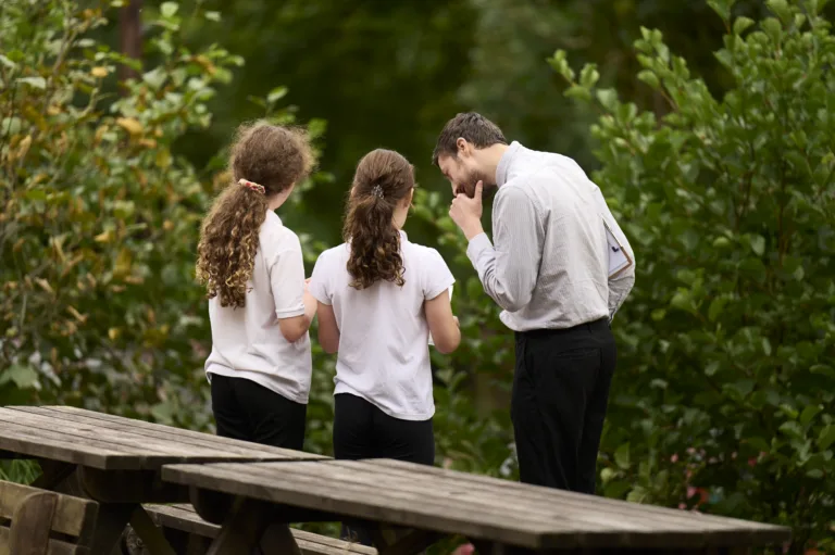 A teach and two school children in the school grounds.